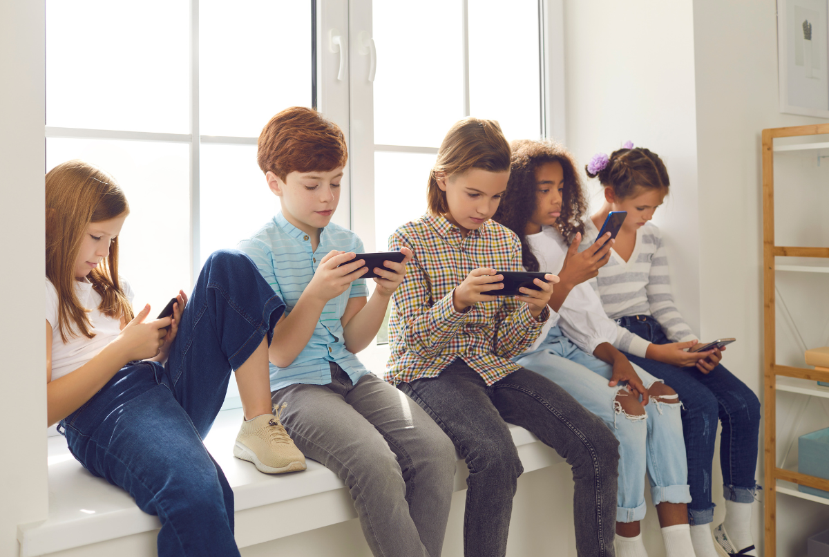 Sekelompok anak bermain game mobile secara multiplayer di sofa