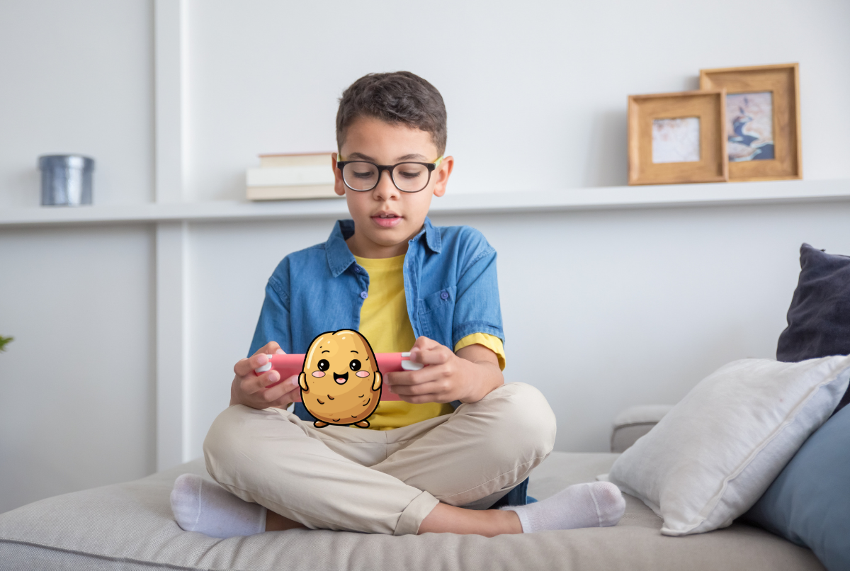 Anak bermain game mobile di smartphone dengan headphone, dikelilingi mainan di meja